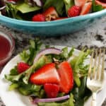 Salad with raspberries and strawberries on plate.
