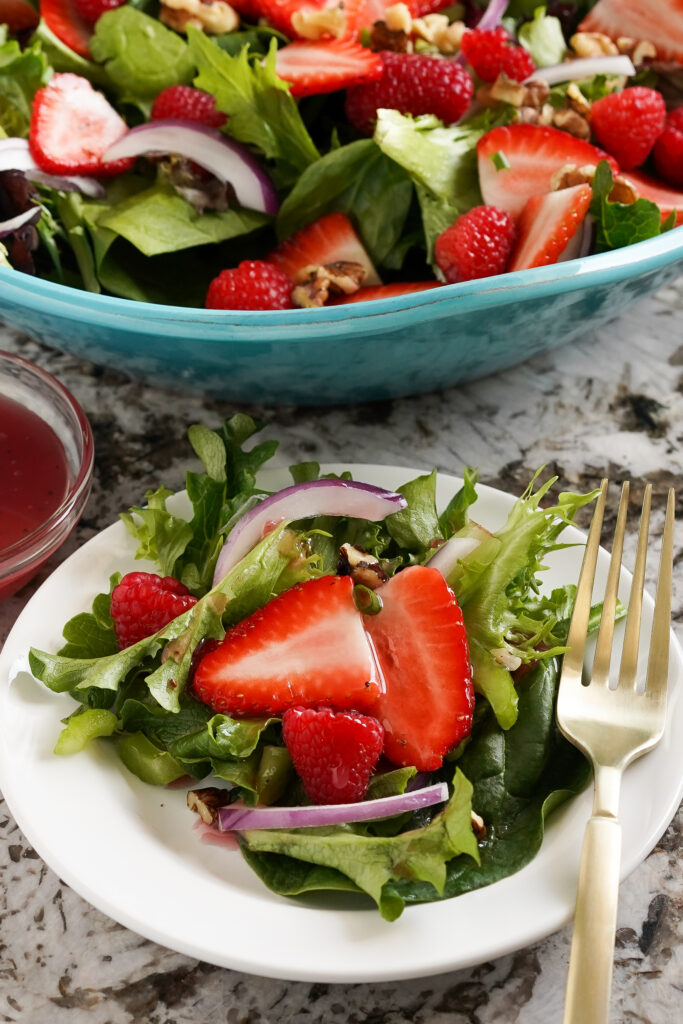 Salad with raspberries and strawberries on plate.