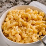 Crockpot mac and cheese with black pepper sprinkled on top in a bowl.