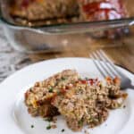 Classic meatloaf made with crackers and cheese on a white plate.