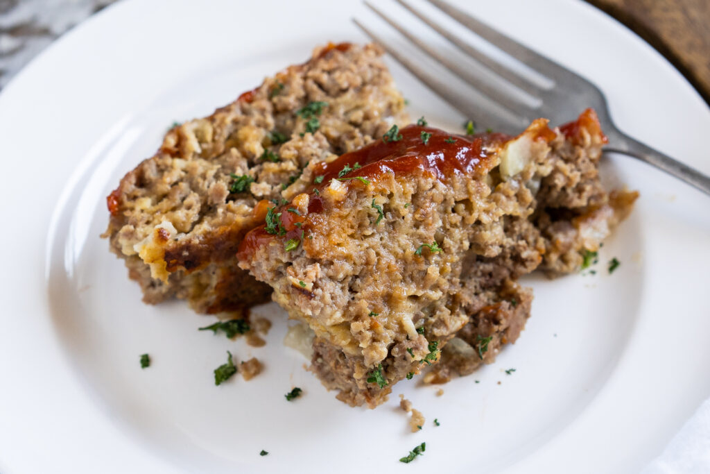 Classic meatloaf made with crackers and cheese on a white plate.
