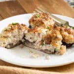 Sausage and cream cheese stuffed mushroom cut open on plate.