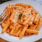 Five Cheese Ziti garnished with parsley and shredded parmesan cheese on a plate.