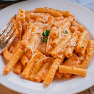 Five Cheese Ziti garnished with parsley and shredded parmesan cheese on a plate.