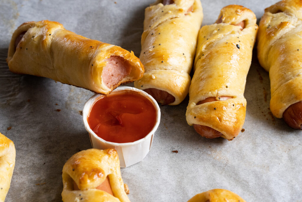 A bite out out of a mummy in a blanket or hot dog baked in crescent roll hot and ready to eat! Perfect for kids and adults!