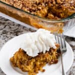 Pumpkin pie crunch bake on a plate with reddi whip on top.