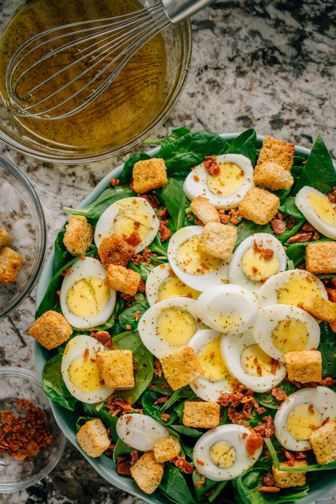 Finished spinach salad. Spinach, egg, bacon bits, and croutons covered in a sweet and tangy homemade vinaigrette.