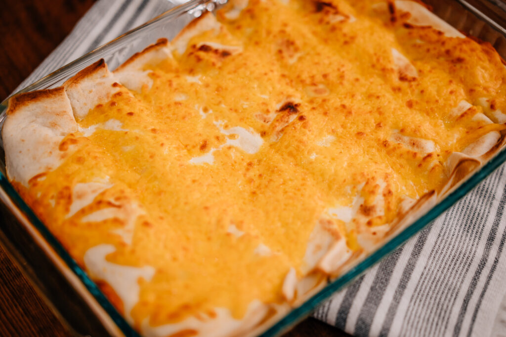 A baking dish of creamy chicken enchiladas golden brown and just out of the oven.
