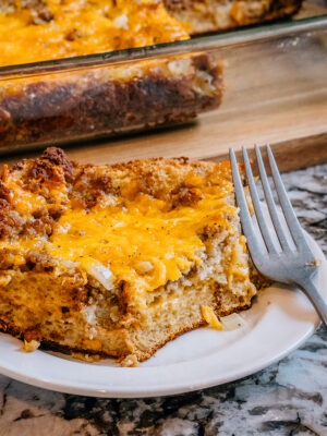 Single slice of fully bake breakfast casserole on a plate. A nice brown outer crust and cheesy melt-in-your-mouth center. Yum!