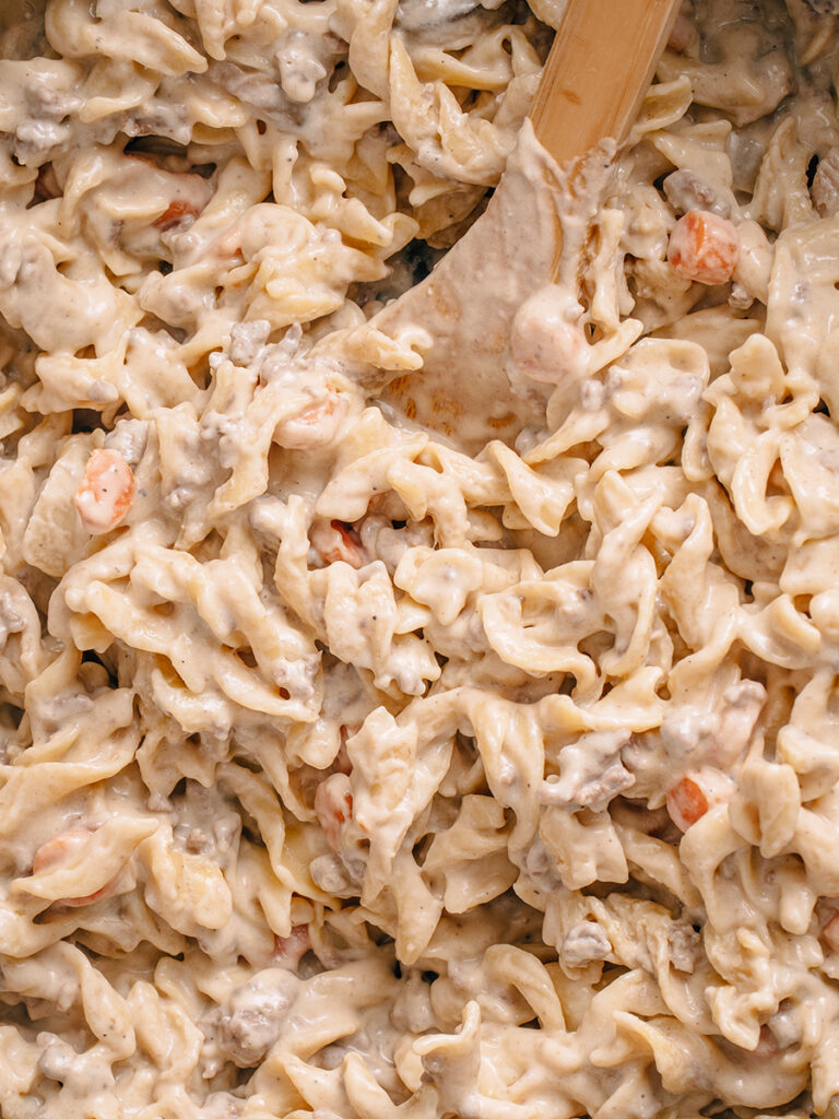 Ground Beef and egg noodles with a homemade white sauce make up this rich and creamy beef stroganoff. Close up view of dish in pan.
