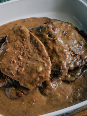 A stack of cube steaks in a serving dish covered in a delicious gravy made of cream of mushroom soup and onion soup mix. Yum!