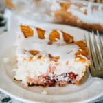 A plated piece of delicious cherry brunch cake topped with a simple powdered sugar, milk, and vanilla extract glaze.