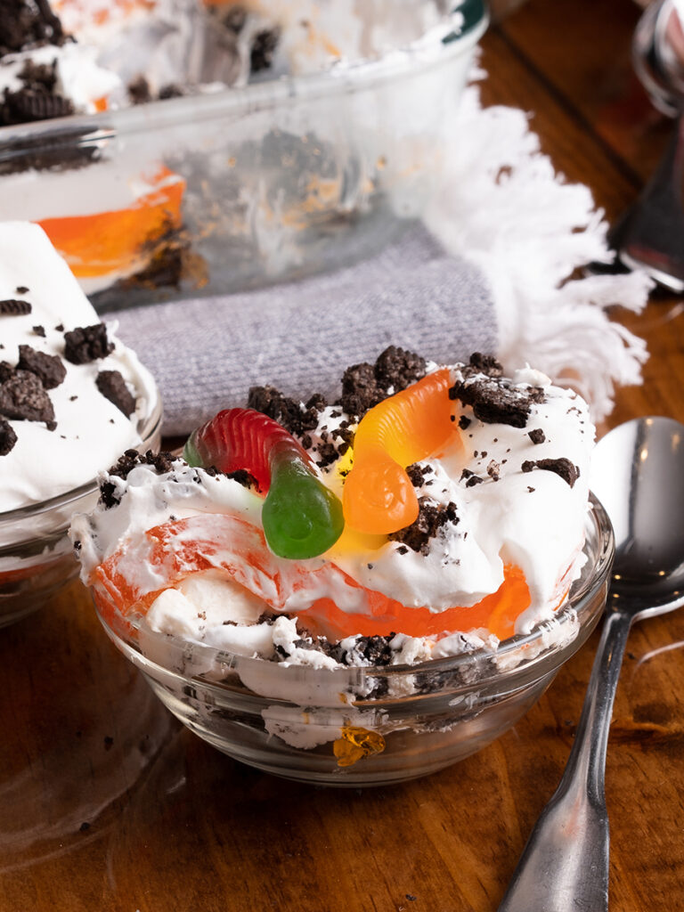 A small bowl of this Halloween dirt dessert garnished with gummy worms coming out of the top of Oreos. A great spooky dessert!