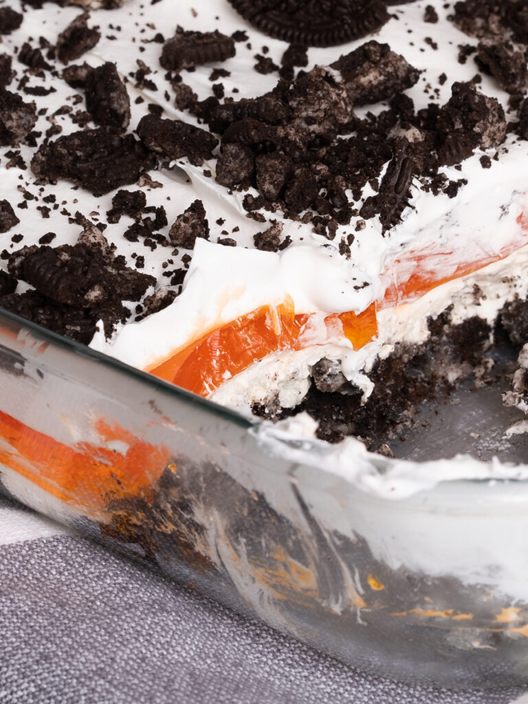 A close view. Layers of crunchy crushed Oreos, creamy cool whip and vanilla pudding, orange jello this Halloween dessert is a twist on the tradition dirt dessert!