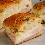 Ham and cheese sliders straight from the oven. Gooey cheese and delicious ham on toasted Hawaiian rolls brushed with a flavorful butter mixture!