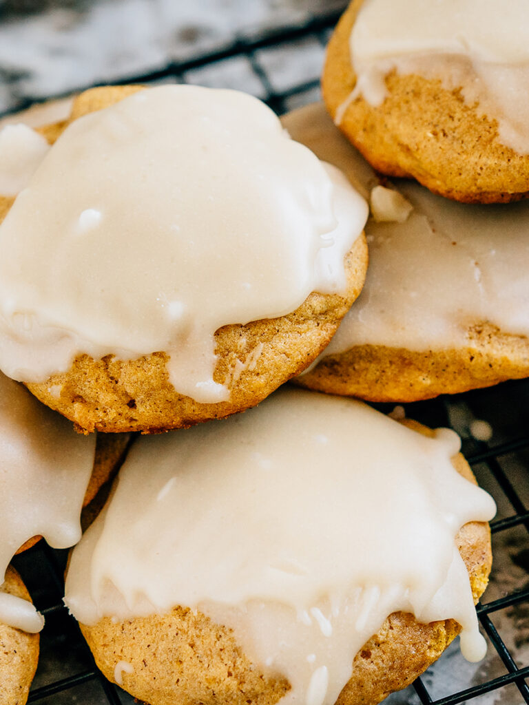 A pile of freshly baked fluffy cake-like pumpkin cookies topped with a simple and sweet glaze.