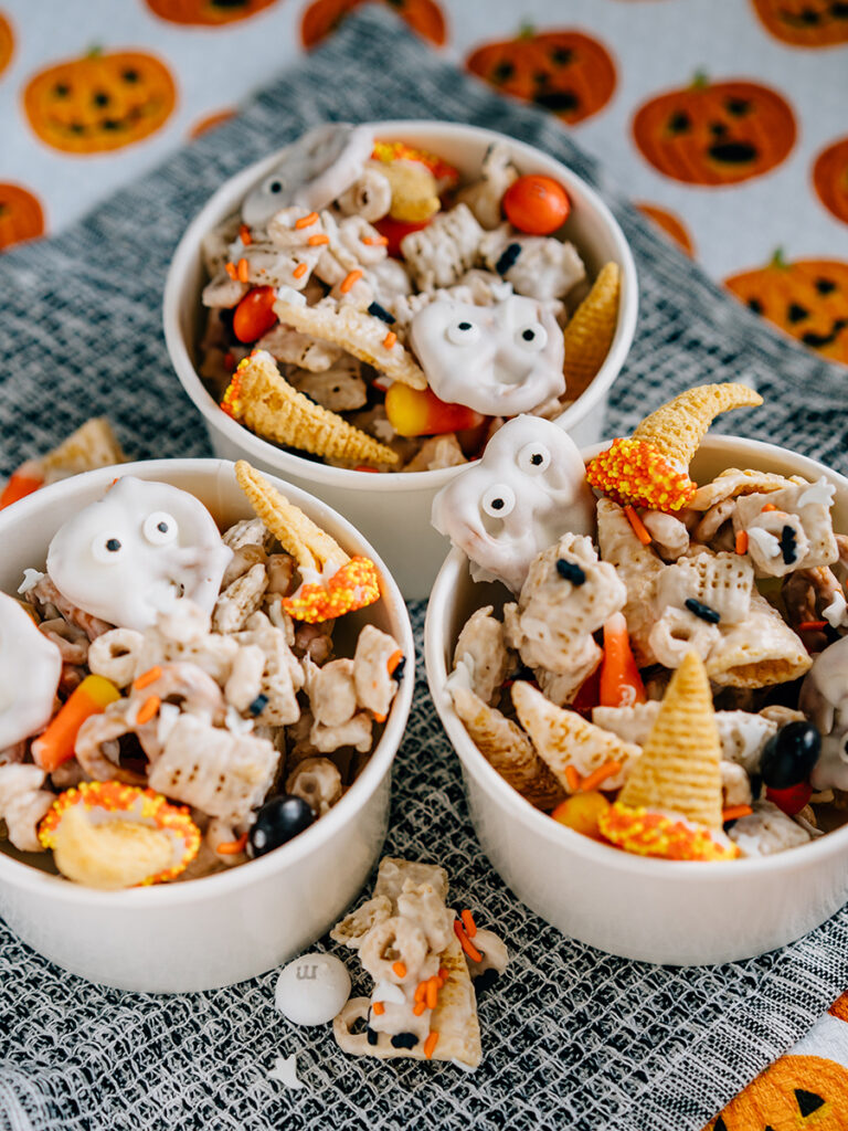 Ghost faces and witches hats mixed with a seasonal white trash mix make this ultimate Halloween party mix spooktacular. Here it is served in ice cream bowls getting for guests!