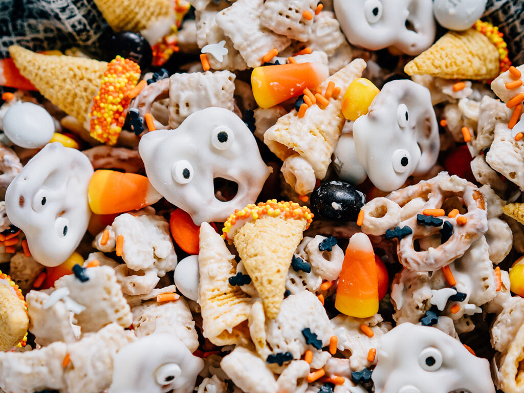 Ghost faces and witches hats mixed with a seasonal white trash mix make this ultimate Halloween party mix spooktacular. Close up view.