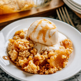Warm apple dump with a scoop of vanilla ice cream and caramel syrup drizzled on top ready to eat!