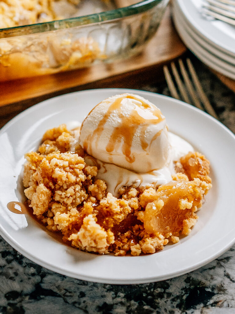 Warm apple dump with a scoop of vanilla ice cream and caramel syrup drizzled on top ready to eat!