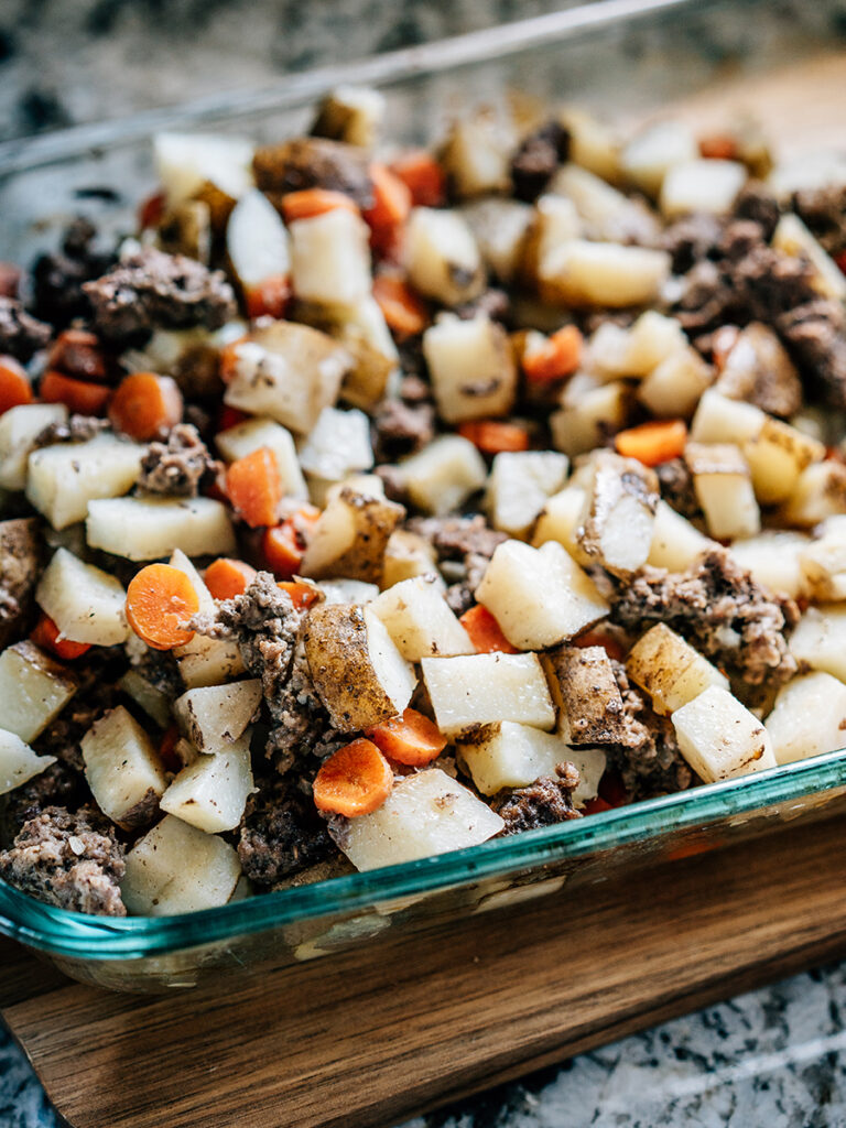 A casserole just baked to perfection: Juicy ground hamburger, tender potatoes and carrots, and wilted onions ready to be garnished with cheese and sour cream and plated to eat!