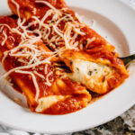 Plated warm and cheesy baked meatless manicotti.