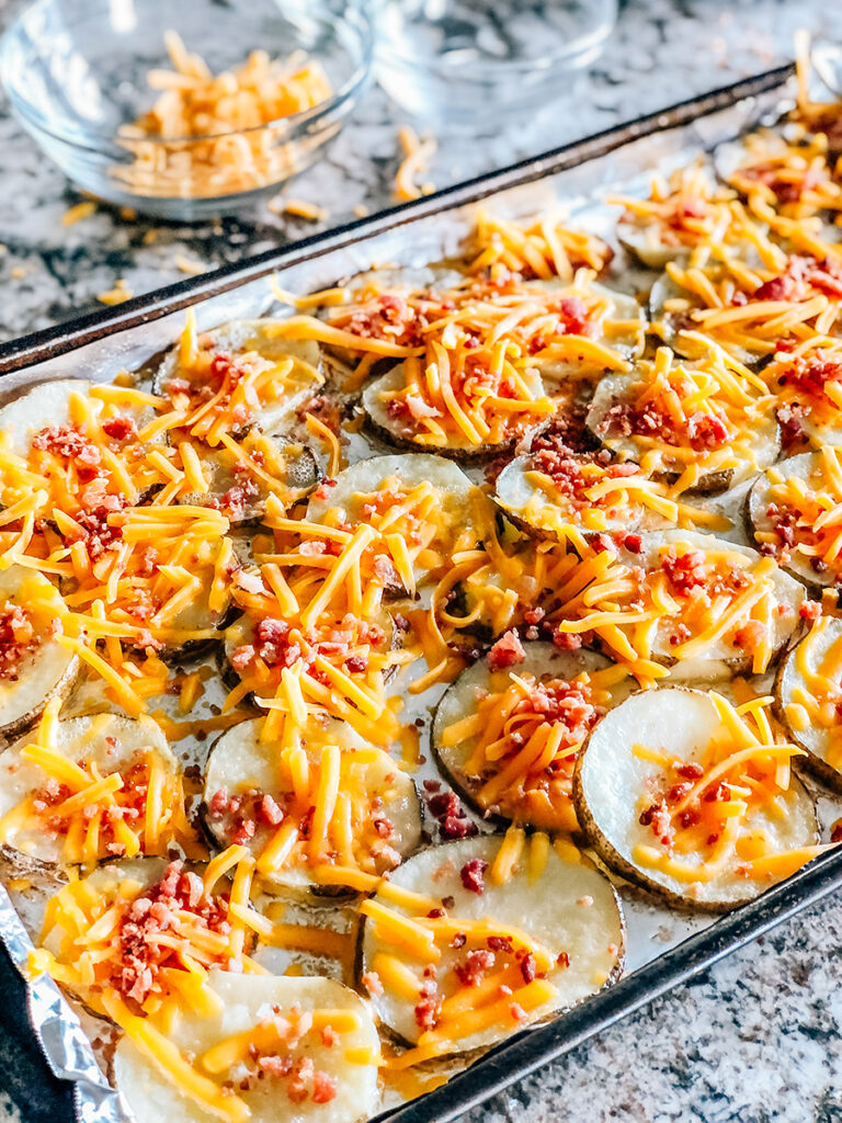 Hot potato slices topped with bacon bits and shredded cheddar cheese.