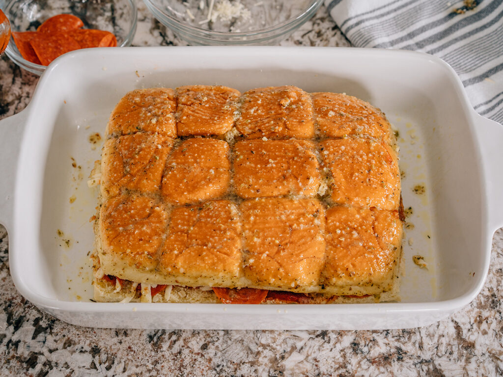 The Hawaiian rolls constructed into pizza sliders and covered in a buttery Italian sauce ready to be baked.
