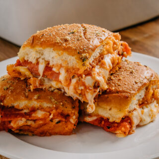 A pile of three warm pizza sliders with melted cheese spilling out the sides waiting to be gobbled up!