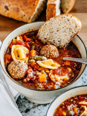 Easy Italian meatball and cheese tortellini soup garnished with parmesan cheese and a crusty bread slice. The perfect warm soup!