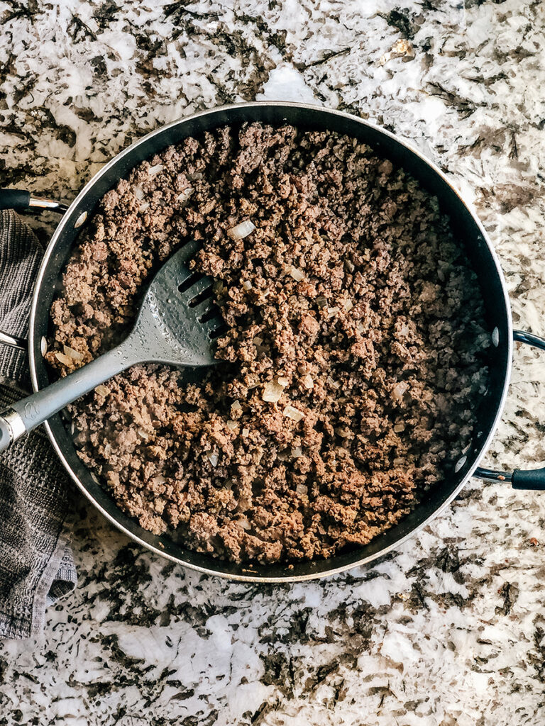 Brown ground beef with onions in a skillet.