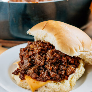 Sloppy joes on a bun with cheese and the skillet in the background.