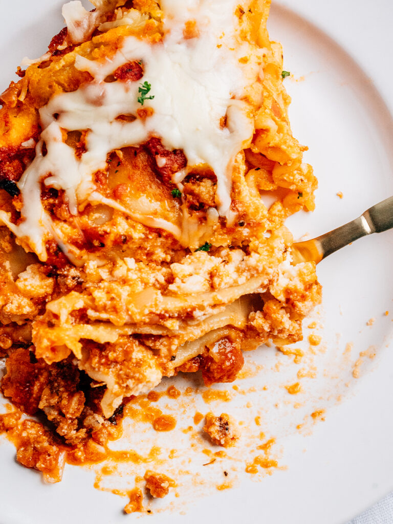 A serving of easy crockpot lasagna plated and ready to eat showing the delicious layers of meat sauce, noodles and cheese!