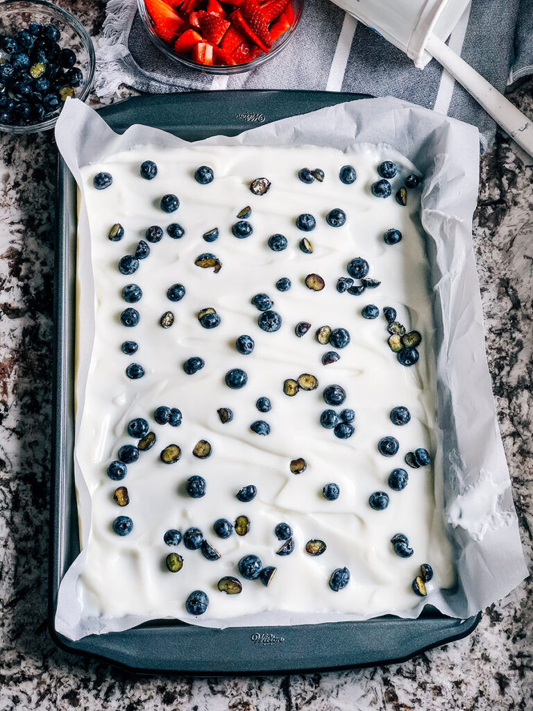 Blueberries sprinkled on top of the layer of vanilla yogurt.