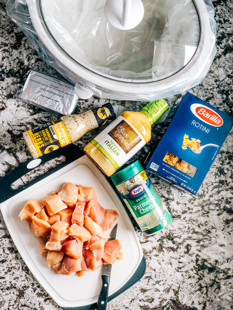 Ingredients for Garlic Parmesan Chicken Pasta: Garlic parmesan wing sauce, Olive Gardens Italian dressing, softened cream cheese, grated parmesan cheese, 2 pounds cubed chicken breast, and 1 pound of pasta.