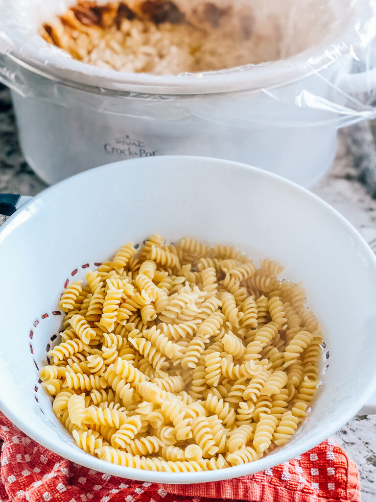 Cooked rotini pasta sitting in front of this easy crockpot meal ready to be added.