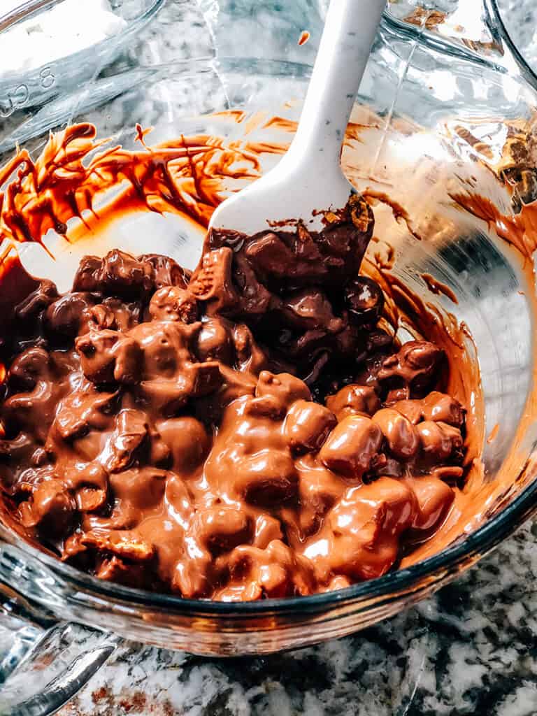 A bowl of melted milk chocolate with crushed graham crackers and mini marshmallows stirred in.