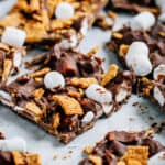 A close up of a piece of s'mores bark where you can see milk chocolate covering the mini marshmallows and golden grahams.
