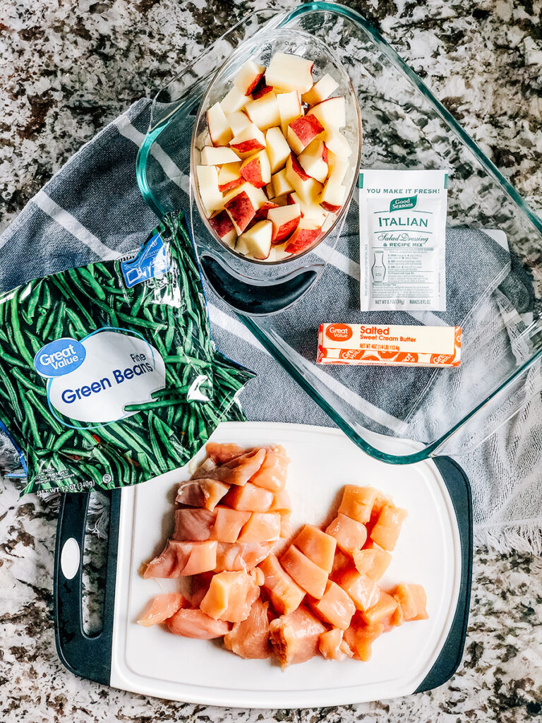 The ingredients for this Italian chicken, green beans and potato dish: Cubed chicken breast and red potatoes, a bag of frozen whole green beans, 1 stick of butter and an Italian salad dressing seasoning packet with a 9x13-inch baking pan.