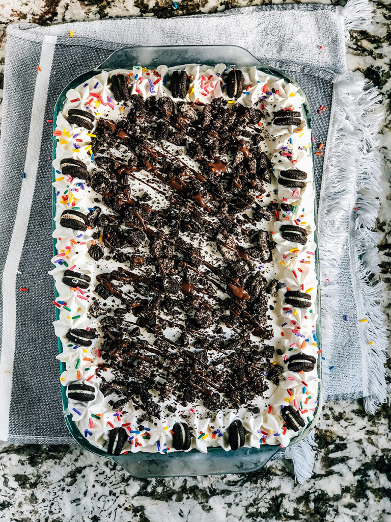 An overview shot of this ice cream cake showing off the delicious and fun Oreos, whipped topping decor, and crushed Oreos.