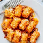 Overview of a plate of tater tot casserole made from sloppy joe, shredded cheese and corn.