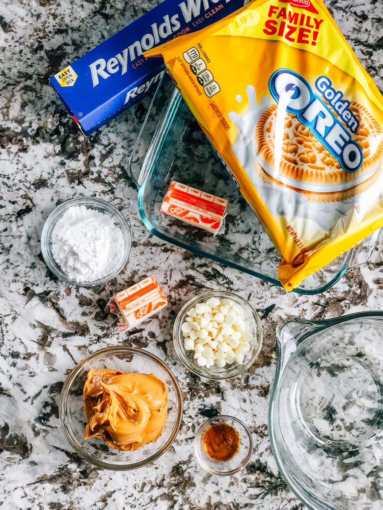 The ingredients to No Bake Peanut Butter Bars: Golden Oreo Cookies, butter, peanut butter, vanilla, white chocolate chips, and powdered sugar.