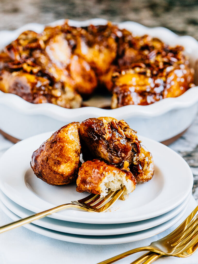 A plate with pieces of monkey bread on them and the pan in the background.