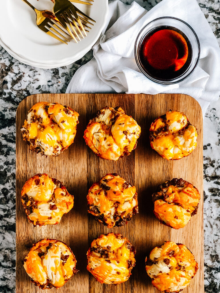 An overview photo of savory breakfast muffins on a serving board with syrup on the side for dipping.