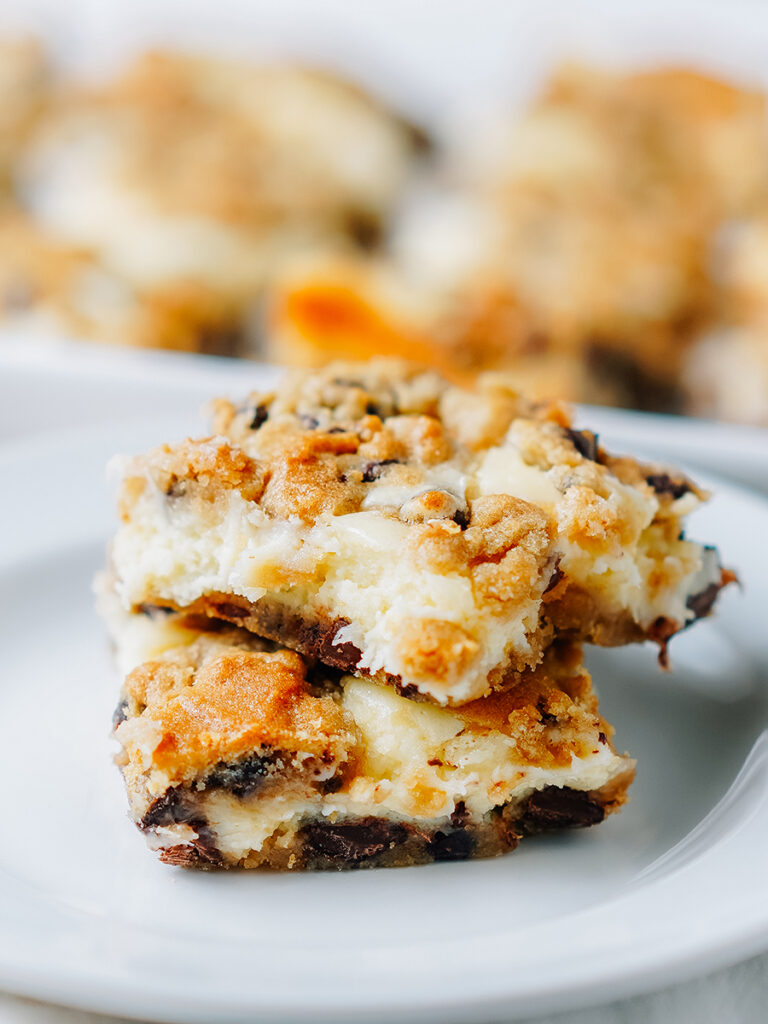 Chocolate chip cheesecake bars stacked on top of each other.