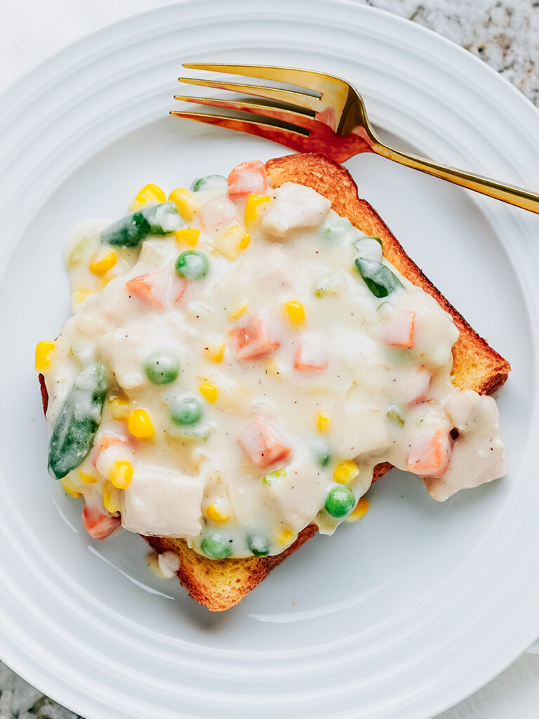 A plate with creamed turkey and vegetables on toasted brioche bread.