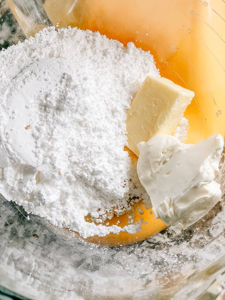 The cream cheese icing ingredients in a mixing bowl ready to be creamed together.