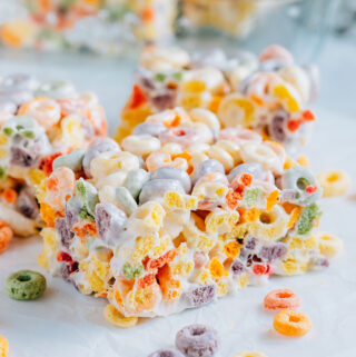 A froot loop cereal treat bar surrounding by more cereal treats and froot loops.
