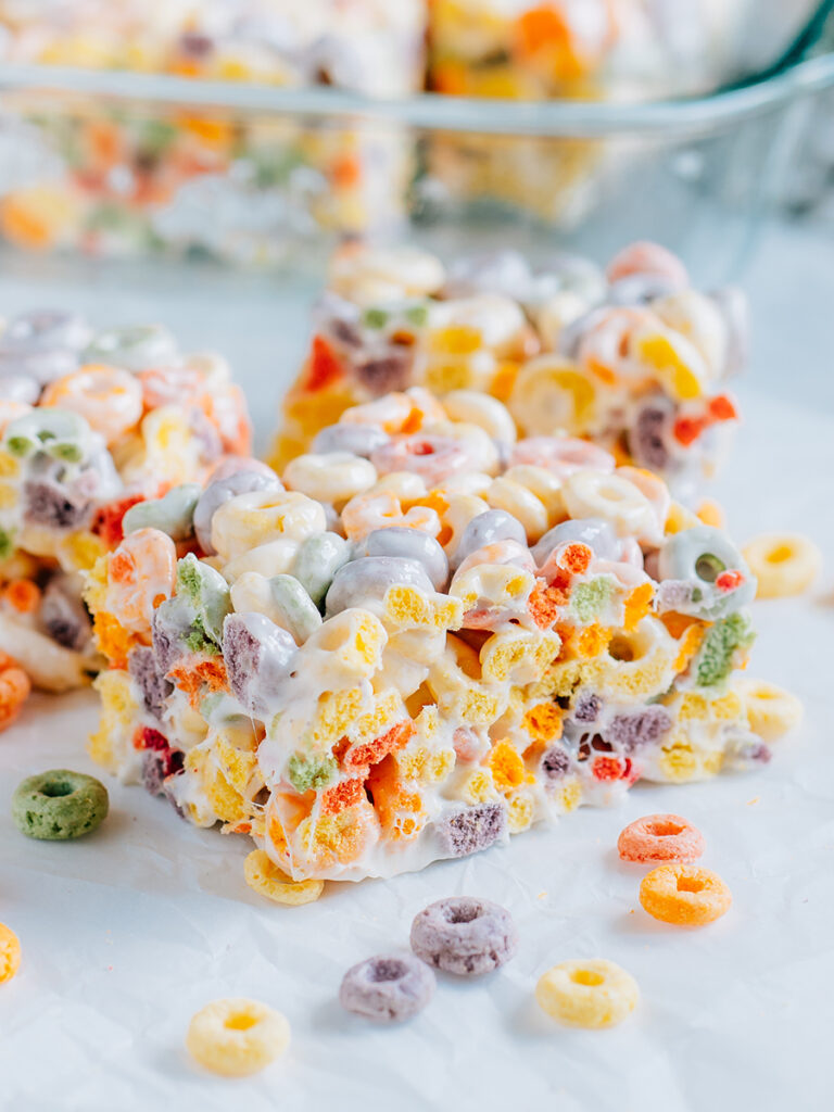 A froot loop cereal treat bar surrounding by more cereal treats and froot loops.