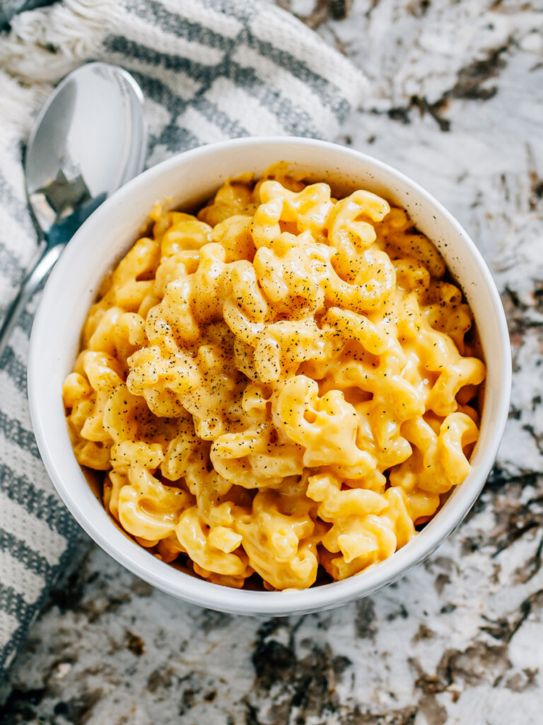 A finish bowl of creamy homemade mac and cheese with a sprinkle of black pepper on top.